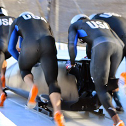 three men in ski suits racing down a track.