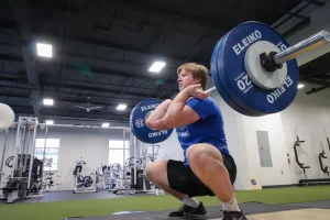 a man squats with a barbell in a MECA gym.