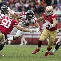 american football player runs with the ball against sports team.