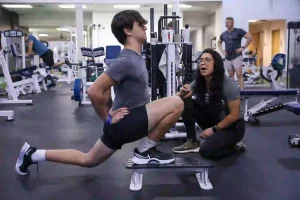 a man and a woman in a MECA gym doing a leg split