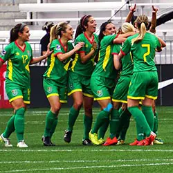 a group of women's soccer players celebrating a goal.