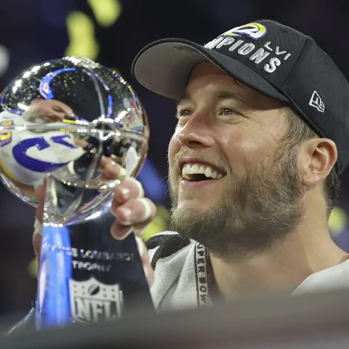 Mathew Stafford holds up the nfl super bowl trophy after winning the super bowl football game.