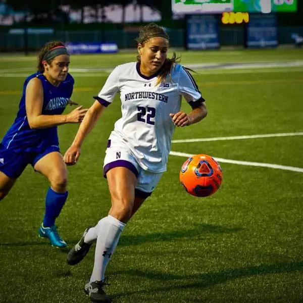 brenna lovera running after a soccer ball on a field.