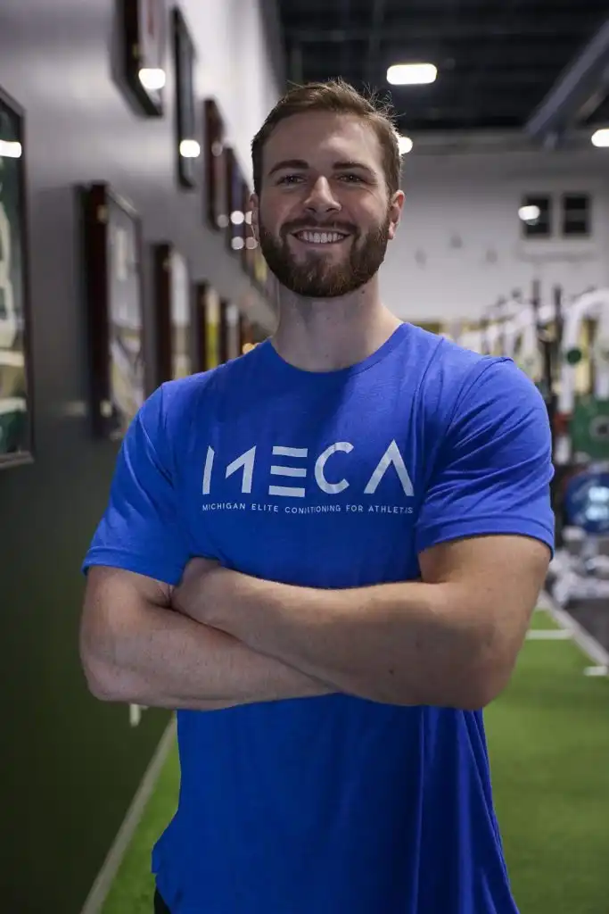 Jared in a blue shirt stands in a MECA gym.