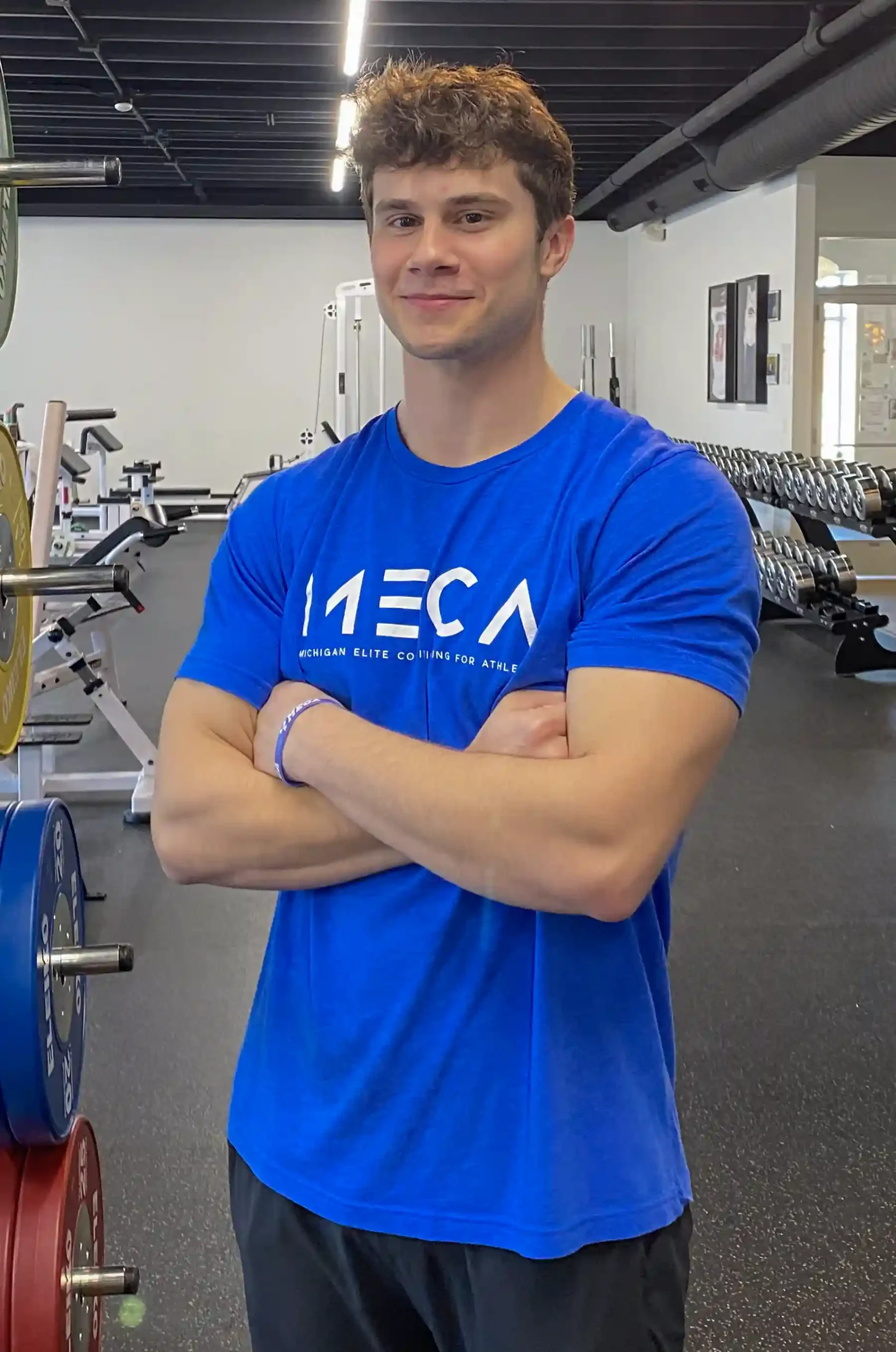 Noah Fye stands in the MECA gym with gym equipment behind him.