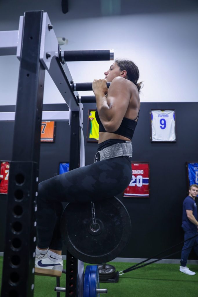 Mckenzie Siroky a female swimmer doing a weighted pull up at MECA
